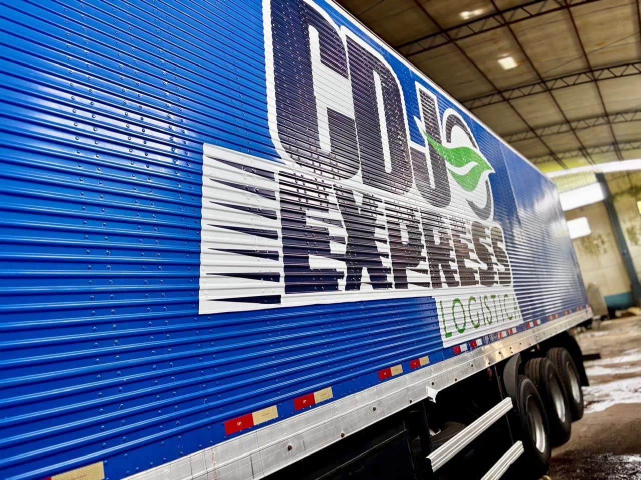 Detalhe lateral de carreta azul com a marca CDJ Express
